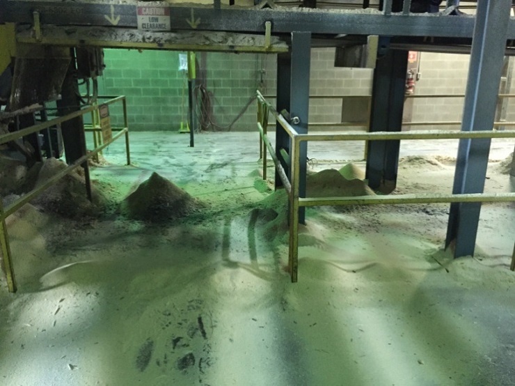 sawmill shop floor with sawdust piles by equipment 