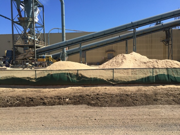 sawmill outdoor auger and silo systems with large sawdust piles