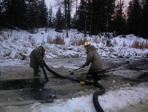 workers using industrial hose in hole cut through ice